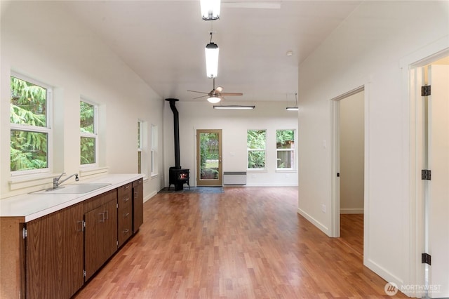 kitchen with light wood finished floors, a healthy amount of sunlight, light countertops, and a sink