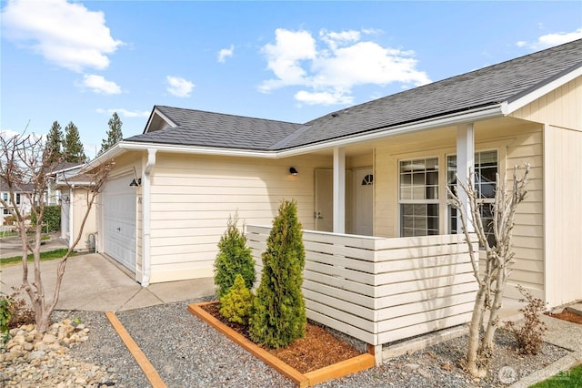 exterior space with an attached garage and roof with shingles