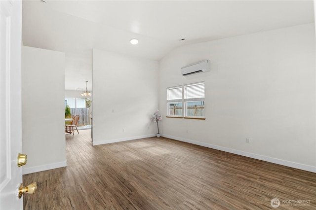 unfurnished room featuring a notable chandelier, a wall mounted AC, wood finished floors, baseboards, and vaulted ceiling