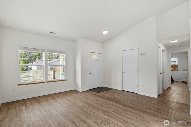 entryway featuring visible vents, baseboards, wood finished floors, and vaulted ceiling