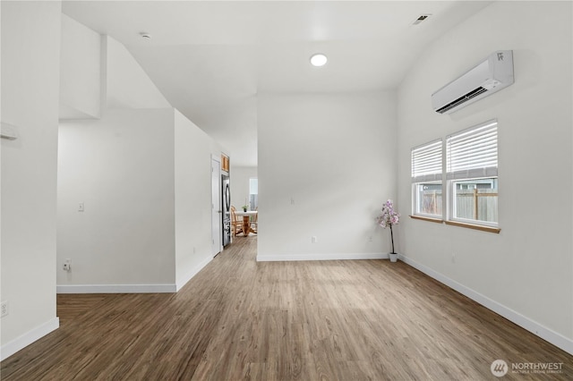 empty room featuring wood finished floors, baseboards, and a wall mounted AC