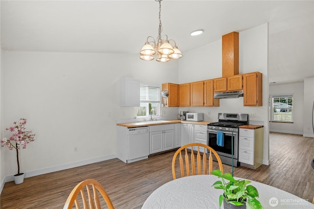 kitchen featuring white appliances, light wood-style flooring, under cabinet range hood, and a sink