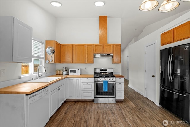 kitchen with a sink, under cabinet range hood, white cabinets, white appliances, and dark wood-style flooring