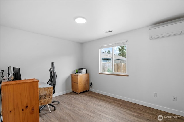 home office featuring a wall unit AC, baseboards, visible vents, and light wood-type flooring