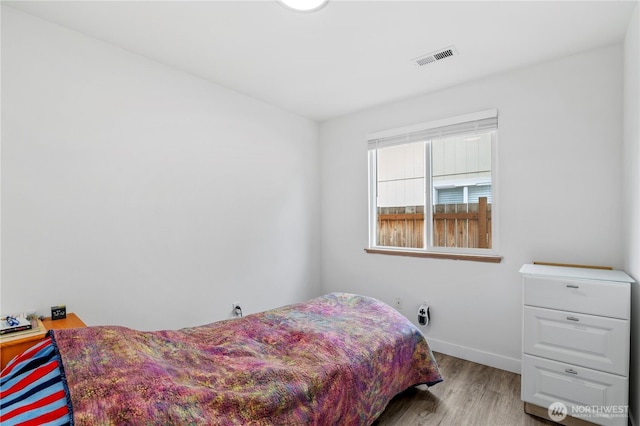 bedroom featuring wood finished floors, visible vents, and baseboards