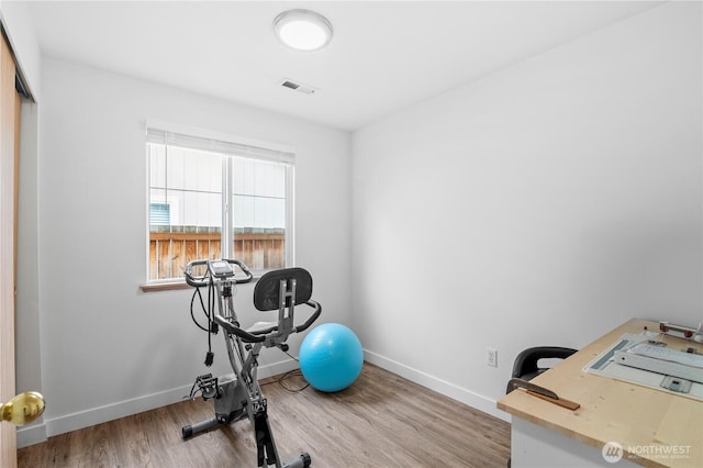 workout area with visible vents, baseboards, and wood finished floors