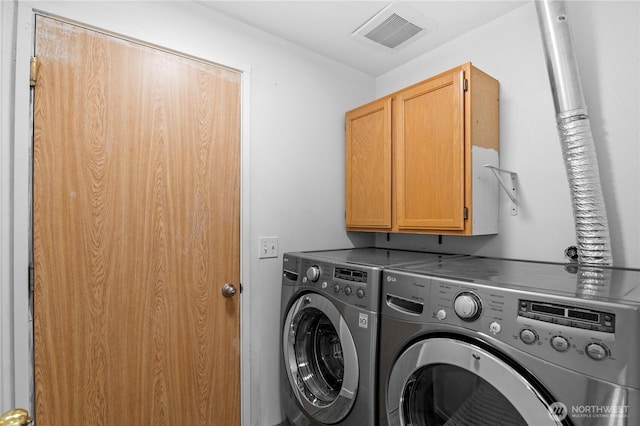 clothes washing area with cabinet space, visible vents, and washer and clothes dryer