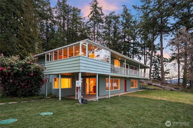 back of property at dusk featuring a lawn