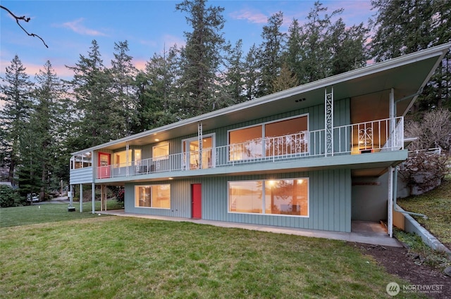 back of house with a balcony and a yard