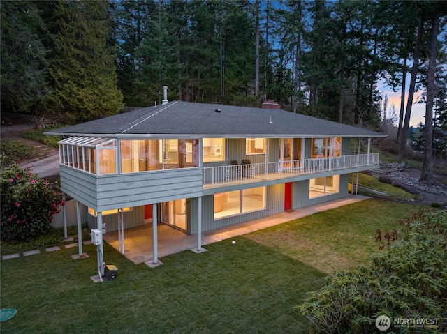 back of property with a lawn, a sunroom, a carport, driveway, and a patio