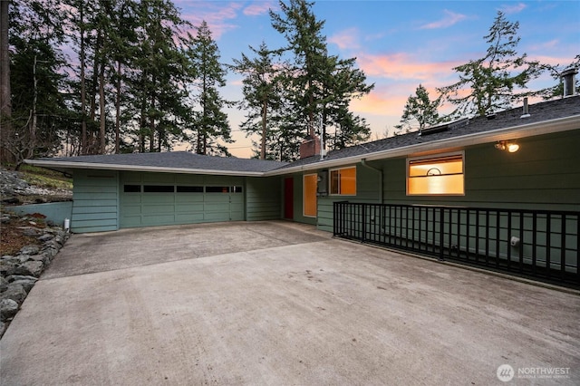 ranch-style house featuring an attached garage, a chimney, and driveway