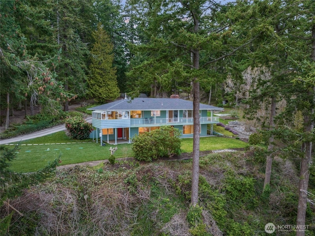 view of front facade featuring a forest view, a wooden deck, and a front yard