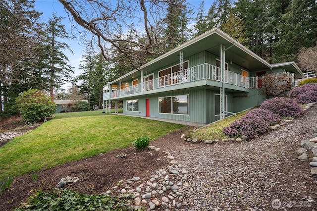 rear view of property with a lawn and a balcony