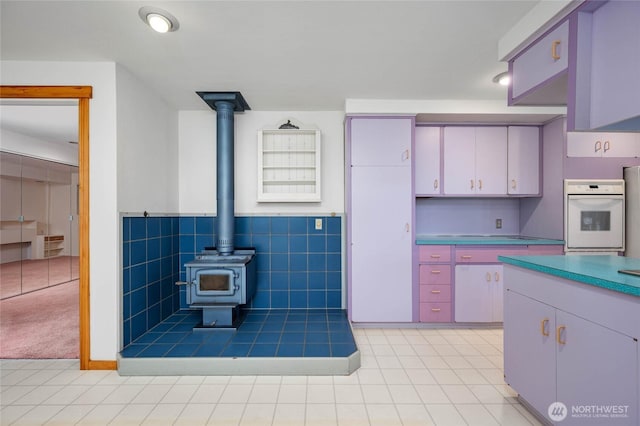 kitchen featuring a wainscoted wall, tile walls, light tile patterned flooring, white oven, and a wood stove