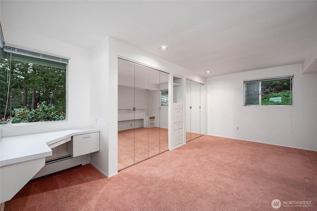 unfurnished bedroom featuring multiple closets, heating unit, recessed lighting, carpet floors, and a baseboard radiator