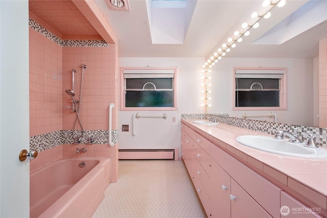 full bath with a sink, tiled shower / bath, baseboard heating, and double vanity