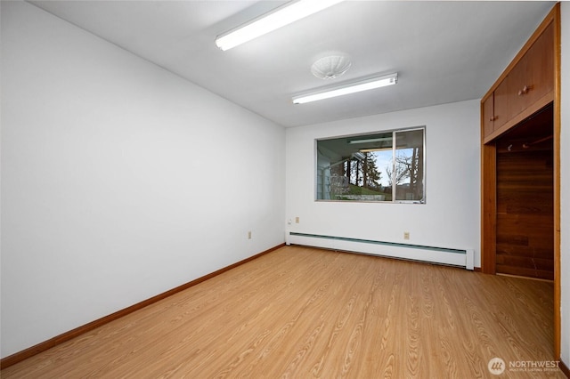 unfurnished room with baseboard heating, baseboards, and light wood-style floors