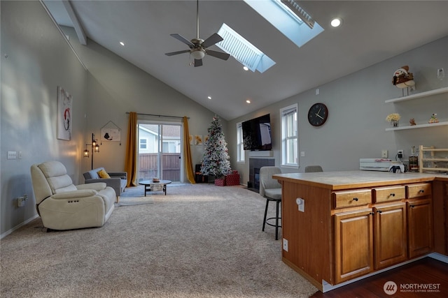 living area featuring a tiled fireplace, dark carpet, recessed lighting, a skylight, and high vaulted ceiling