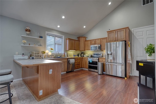 kitchen with visible vents, a breakfast bar, a peninsula, stainless steel appliances, and tile counters