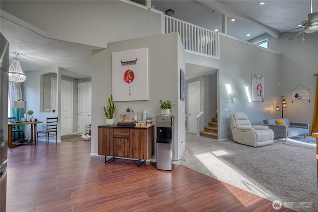 living area with stairway, wood finished floors, recessed lighting, ceiling fan, and a towering ceiling