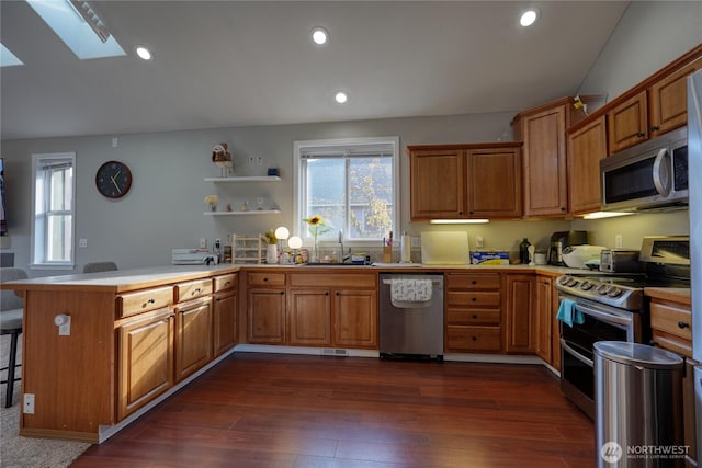 kitchen with a sink, a peninsula, brown cabinetry, and stainless steel appliances