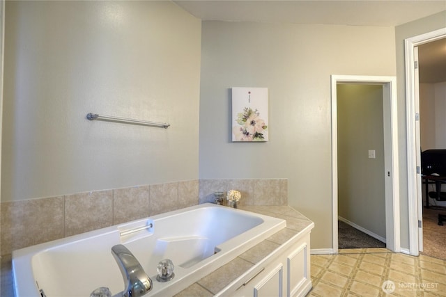 bathroom with tile patterned floors, a bath, and baseboards