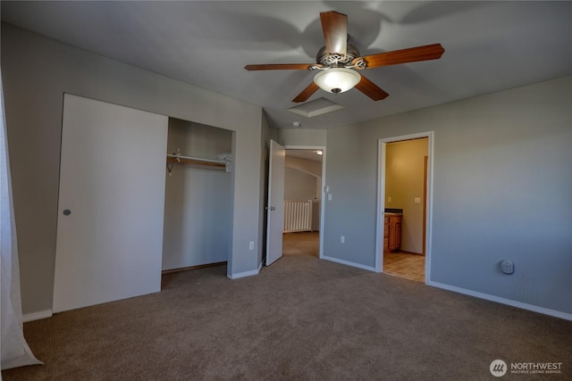 unfurnished bedroom featuring a closet, carpet floors, baseboards, attic access, and ceiling fan