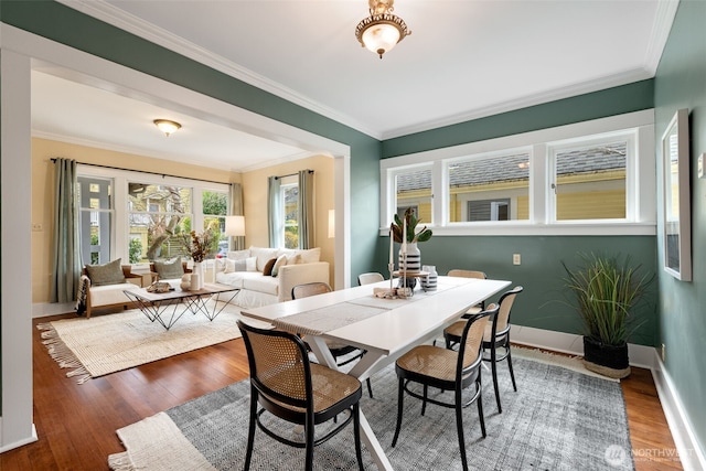 dining room featuring crown molding, baseboards, and wood finished floors