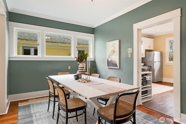 dining space with a healthy amount of sunlight, light wood-type flooring, and ornamental molding