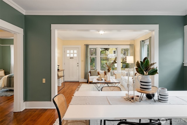 dining room with baseboards, wood finished floors, and crown molding