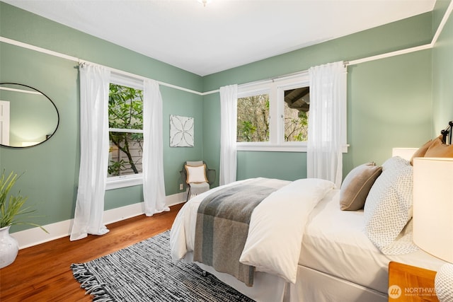 bedroom featuring multiple windows, baseboards, and wood finished floors