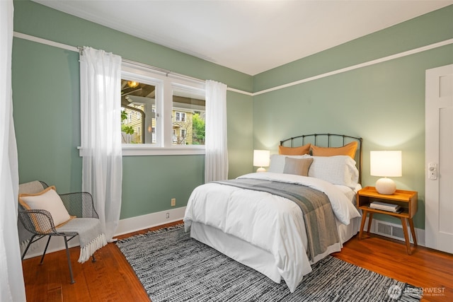 bedroom with visible vents, baseboards, and wood finished floors