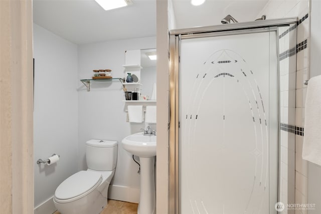 bathroom featuring a sink, baseboards, toilet, and a stall shower