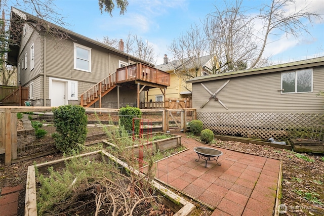 back of property with fence, a garden, a wooden deck, stairs, and a patio area