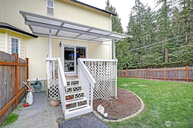 entrance to property featuring a lawn, a wooden deck, and fence