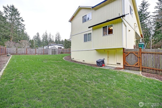 back of house featuring a storage shed, an outdoor structure, a yard, and a fenced backyard