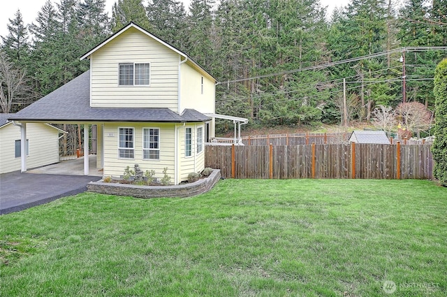 view of front facade featuring a front lawn, a carport, driveway, and fence