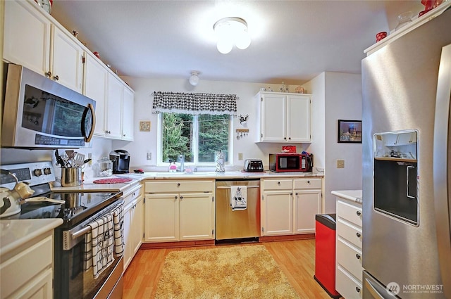 kitchen with a sink, light countertops, light wood-style floors, and stainless steel appliances