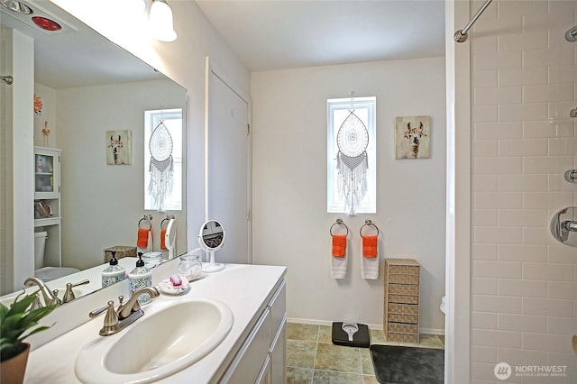 full bath with vanity, a healthy amount of sunlight, and a shower