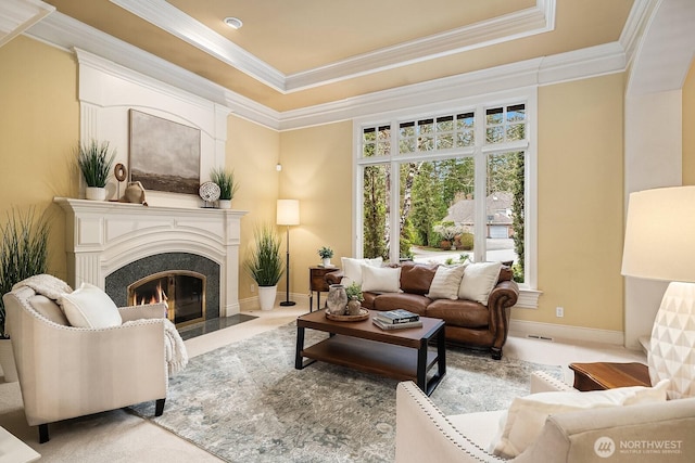 living room featuring a raised ceiling, a fireplace with flush hearth, and ornamental molding