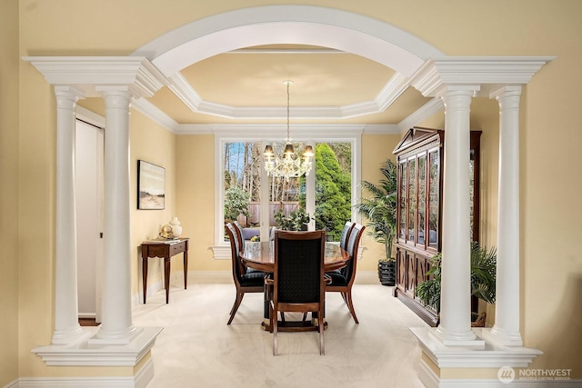 dining area with ornate columns, an inviting chandelier, a tray ceiling, ornamental molding, and light colored carpet