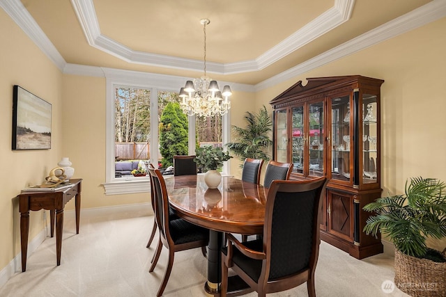 dining area with baseboards, a chandelier, a tray ceiling, ornamental molding, and light carpet