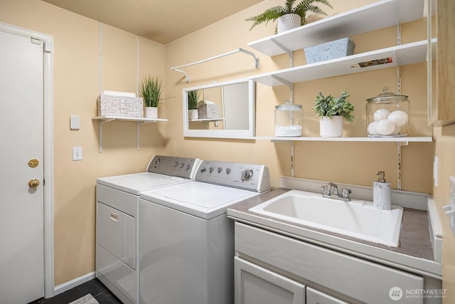 clothes washing area featuring washing machine and clothes dryer, cabinet space, and a sink