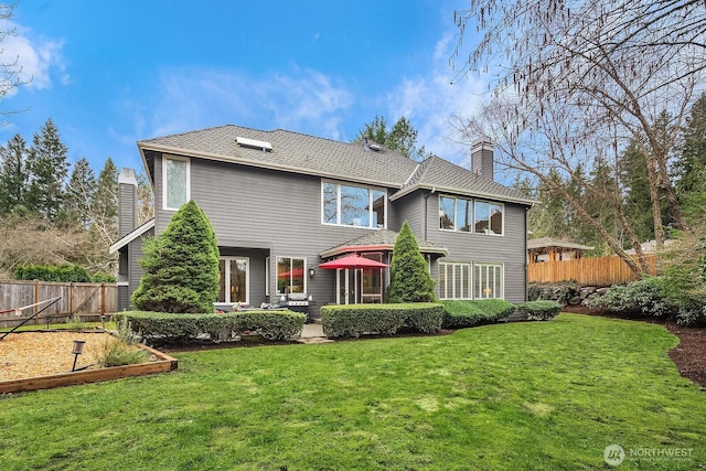 rear view of house with a yard, a patio area, a chimney, and fence