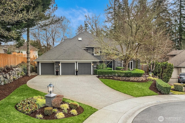 view of front of house with a front lawn, fence, roof with shingles, a garage, and driveway