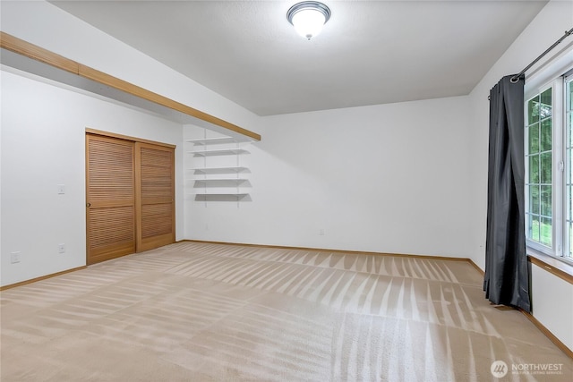 unfurnished bedroom with multiple windows, baseboards, and light carpet