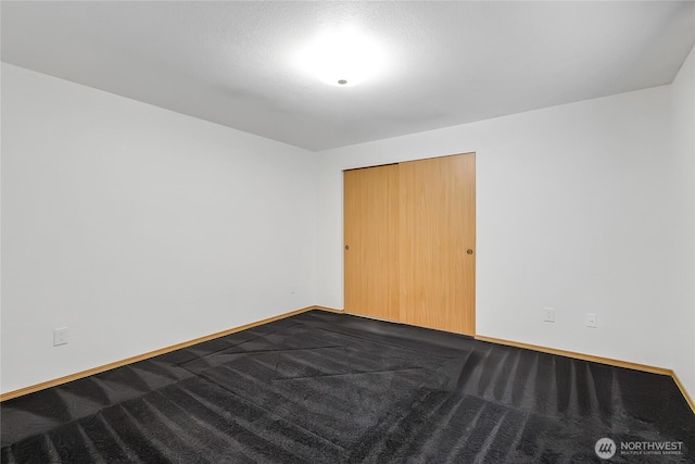 unfurnished bedroom featuring dark carpet and baseboards