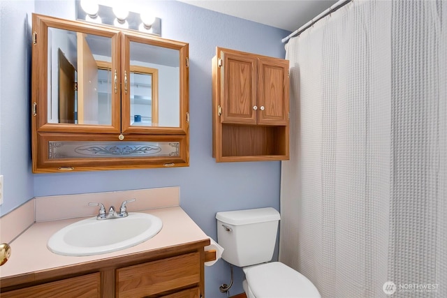 bathroom with curtained shower, toilet, and vanity