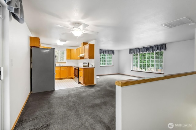 kitchen featuring visible vents, stainless steel appliances, light countertops, light colored carpet, and ceiling fan