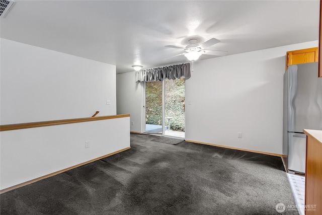 unfurnished room with visible vents, dark carpet, baseboards, and ceiling fan